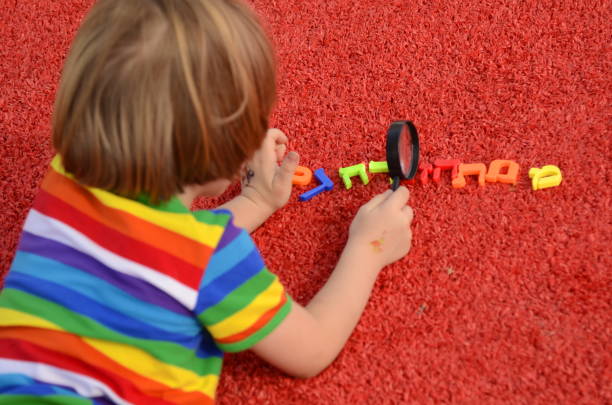 niño jugando en el suelo con una lupa y letras hebreas